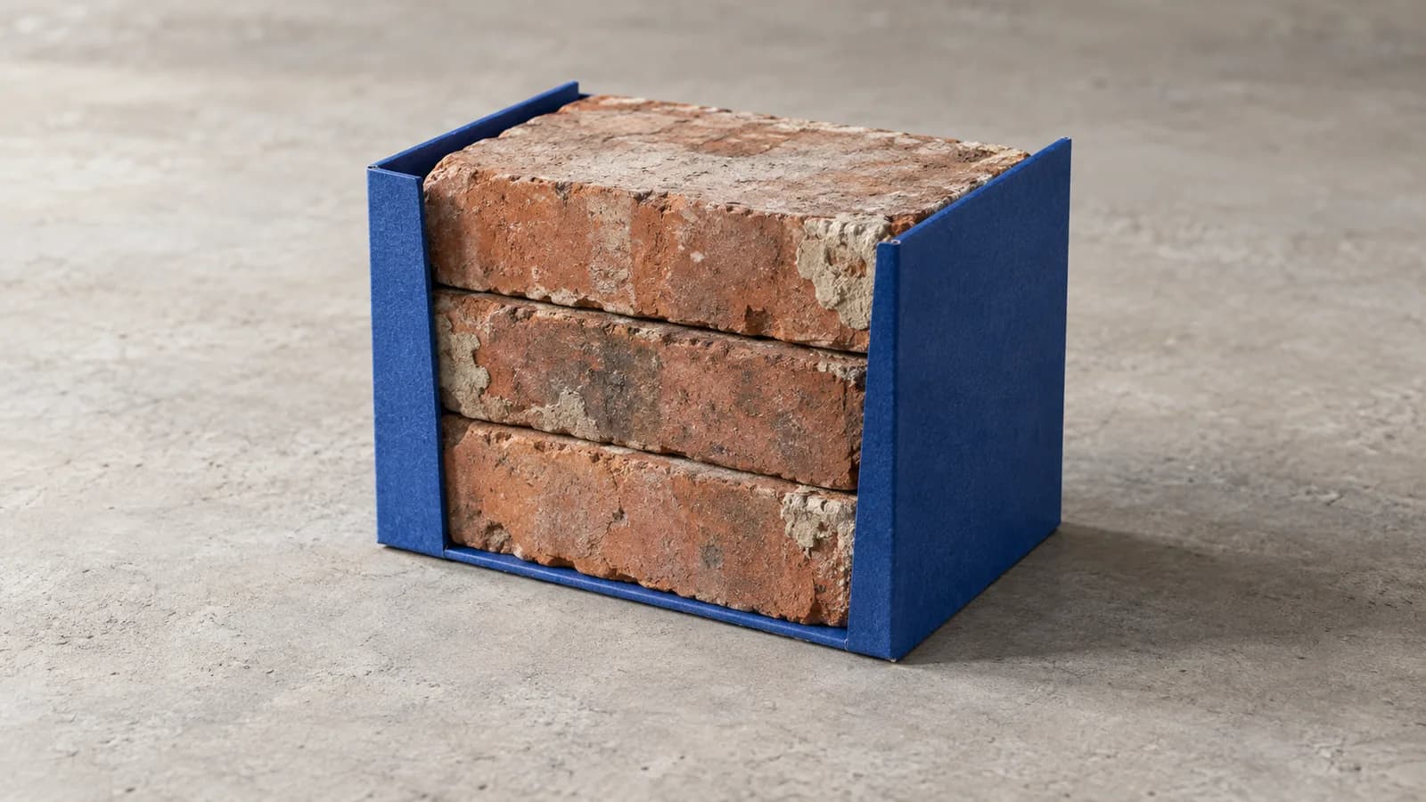 Beton yüzey üzerinde kobalt mavisi koruyucu kılıfa yerleştirilmiş eski kil tuğlalar